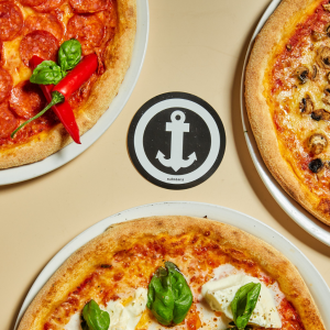 Drei Pizzen nur zu einem Viertel im Bildausschnitt zu sehen, in der Mitte ein Substanz Anker Aufkleber
